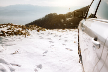 Car parked on the roadside on a mountain top covered in snow. Sunset on a ski resort.