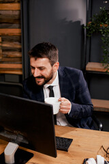 Young businessman using computer in his office. Handsome man on coffee break.