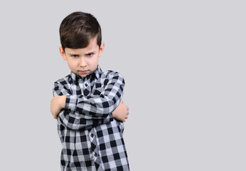 Boy in gray shirt is angry on studio gray isolated background, Unhappy schoolboy. The boy is offended