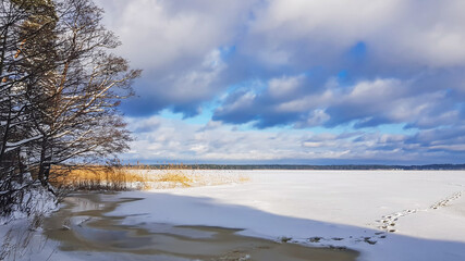 Panorama of a snowy lake with footprints in the snow in Riga, Latvia