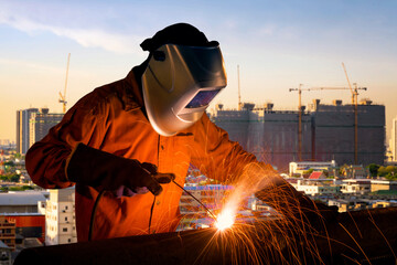 Industrial worker welding steel structure for infrastructure building project with construction...
