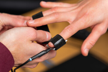 close-up, a man puts on a woman's hand polygraph sensors, a truth detector, to pass a polygraph. Selective focus