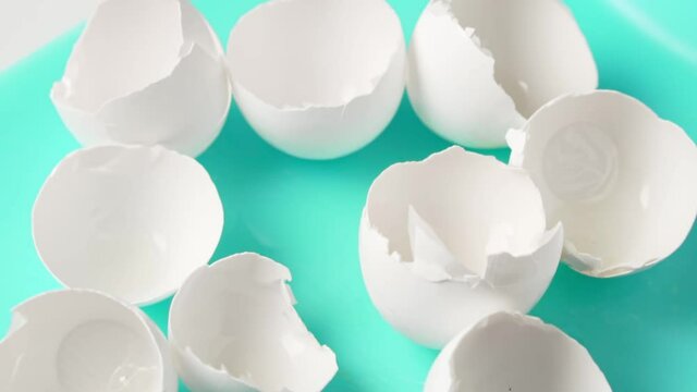 Empty eggshell falls onto a turquoise cutting board, slow motion. Products containing calcium.