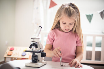 Little girl with microscope in her room.