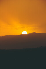 Close up of a big sun falling down under the mountains