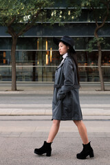 classy asian woman walking in the city with hat