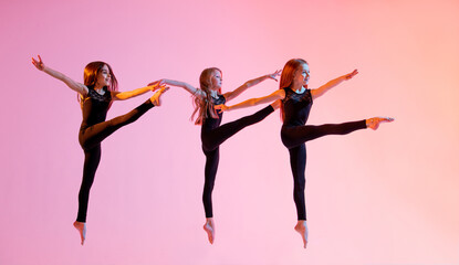 group of three ballet girls in black tight-fitting suits jumping on red background with their long hair down.
