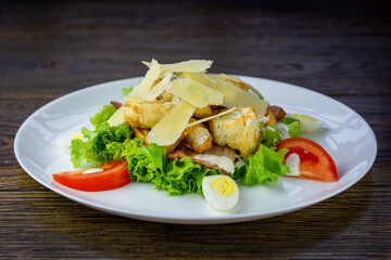 Caesar salad served on the white plate on the wooden table