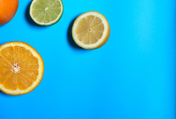 Split oranges, limes and lemons with skin on a blue background. CITRUS CITRIC