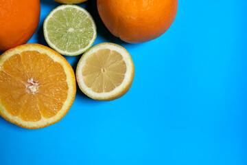 Whole and split oranges, limes and lemons with skin on a blue background. CITRUS CITRIC