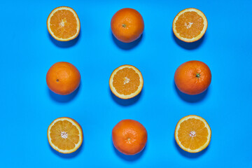 Whole and split oranges on a blue background. CITRUS CITRIC
