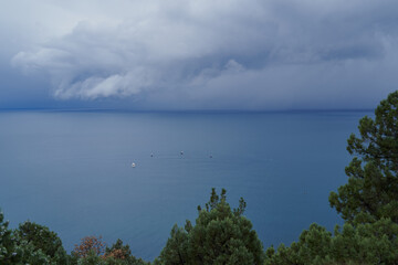 Yachts and motor boats are drifting in the sea near weather front with clouds.