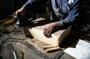 close-up of carpenter fixing wooden drawer in carpentry shop. Manual work with hands. 