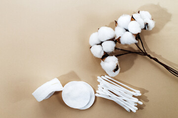 Obraz na płótnie Canvas fluffy cotton flower cotton pads and cotton swabs on beige background with copy space. hygienic disposable product