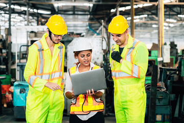 Work at factory.engineer woman and workers man team working together in safety work wear with white and yellow helmet using laptop computer.in factory workshop industry meeting professional