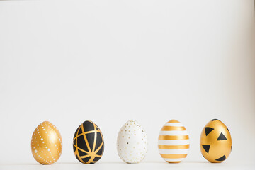 Easter golden decorated eggs stand in a row on white background. Minimal easter concept. Happy Easter card with copy space for text. Top view, flatlay.