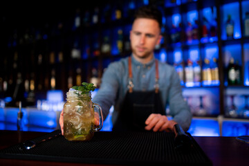 Young guy a working as a bartender while preparing cocktails in a pub