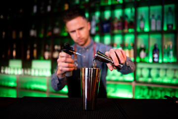 Young guy working as a bartender preparing cocktails in a pub
