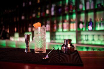 Young guy working as a bartender while preparing cocktails in a pub