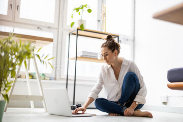 Creative young woman working on laptop in her studio
