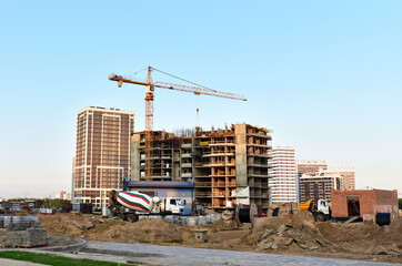 Heavy mixer concrete truck waiting for to be loaded concrete at construction site. Tower crane...