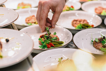 chef is serving beef tartar with baked toast and egg and cucumbers on a buffet