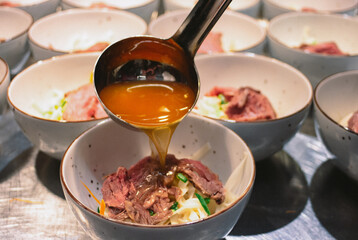 chef is serving fobo soup with meat on a buffet