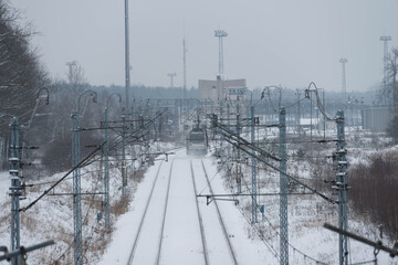 Dwutorowy szlak kolejowy zimą z przejeżdżającą lokomotywą elektryczną. © boguslavus