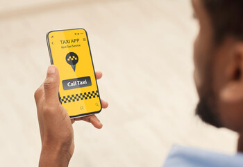 Online taxi service application. Closeup of black guy booking car via mobile phone app, waiting for cab transfer at home