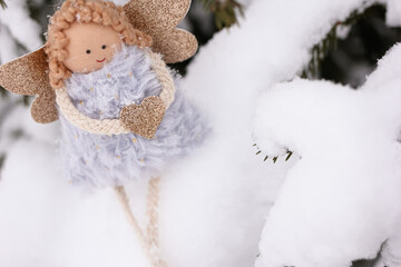 A soft textile doll with golden heart in hands sitting on the snow. Valentine’s Day, love, Merry Christmas, New Year concept.