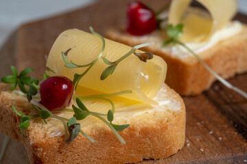 Mini toast with butter, cheese and watercress micro greens. Breakfast concept, close-up and blur