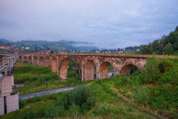 Arched old brick railway bridge in the picturesque mountains among the forest of meadows tourist trail Carpathians