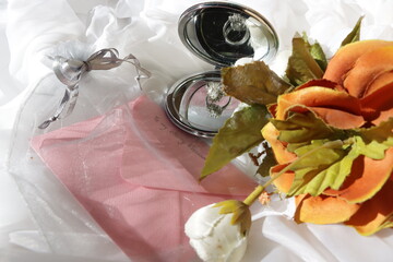 Silver beautiful Engagement Marriage ring reflected in a beauty mirror placed on net decoration with bridal bouquet and gift card in pretty pouch of silver color