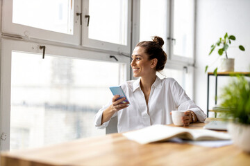 Creative business woman using smartphone in loft office
- 410127359