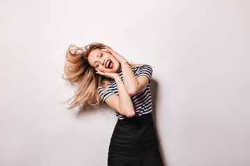 Fototapeta premium Lady with snow-white smile and red lips is dancing vigorously. Photo of blonde girl on white background