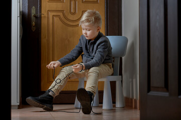 Child tying his shoelaces for himself, Children learning at home to help himself with difficult task.