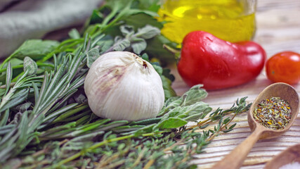 Olive oil in a glass jar and spicy herbs on a wooden table close-up, copy space. Home cooking, Italian recipes.