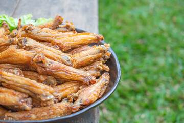Fried chicken wings with fish sauce with salad vegetables on a white plate placed on a wooden table. Close-up photo. Space for text. Concept of foods