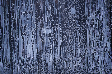 Snow flakes, snow and ice flowers, snow painting on dark fence. Winter background with ice texture.