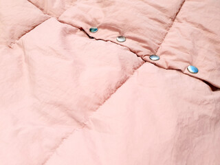 Down jacket fabric background and metal buttons or rivets, pink puffer jacket texture. Top view