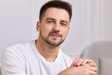 portrait of smiling handsome young man in earphones is talking to somebody on video call.
