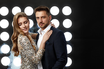 beautiful glamorous couple posing against the backdrop of spotlights and smoke. night life. copy space