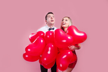 Fototapeta na wymiar Valentines day. Surprised young couple with balloons heart on pink background