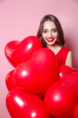 Happy Valentines Day. Beauty girl with red hearts balloons laughing on pink background