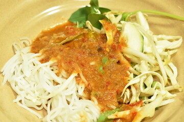 rice noodles dressing fish coconut milk curry sauce and fresh vegetable on plate
