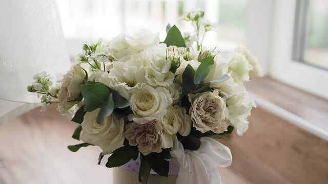 Bride's wedding bouquet of white roses stands on the floor during the day