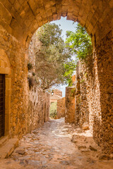 narrow alley with cobblestones and stone walls in medieval Monemvasia, Peleponnese, Greece