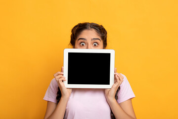 Surprised Indian woman showing blank tablet screen