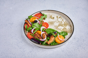 Homemade styling salad with fried eggplants, tomatoes, arugula, spinach, lettuce and sauce on a ceramic plate on light background, close up, copy space