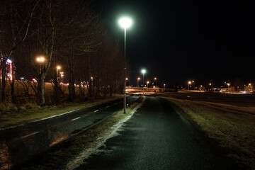 Ein spärich beleuchteter Fußweg und Radweg am frühen Morgen in Reykjavik